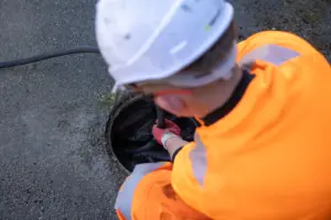 Member of the team surveying customer drain